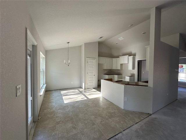 kitchen featuring high vaulted ceiling, an inviting chandelier, and white cabinetry