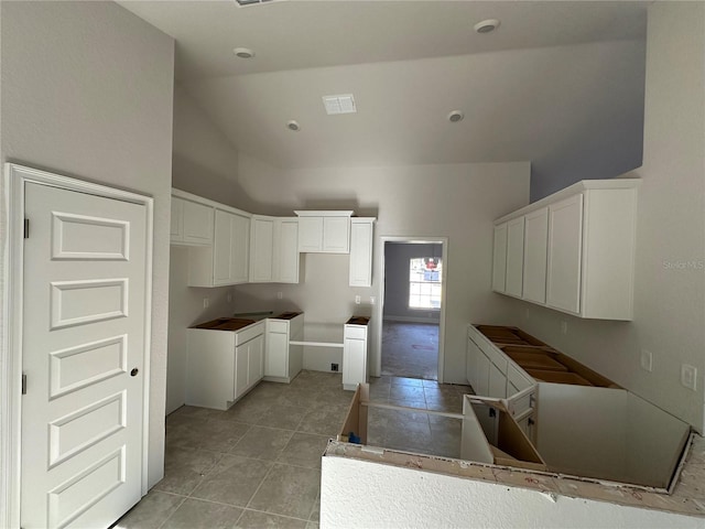 kitchen featuring high vaulted ceiling, white cabinetry, and light tile patterned floors