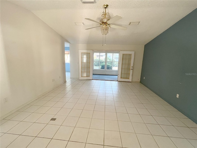 tiled empty room featuring ceiling fan, lofted ceiling, a textured ceiling, and french doors