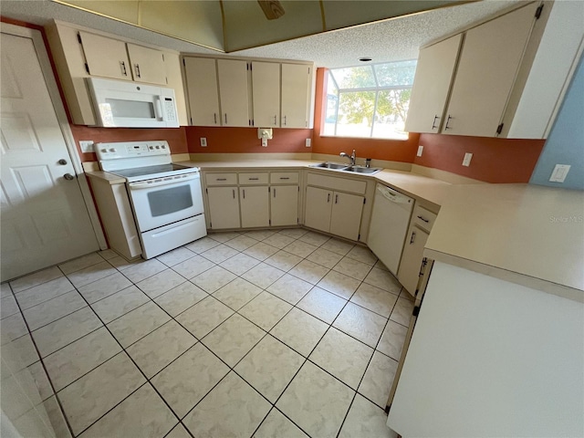 kitchen with cream cabinetry, a textured ceiling, white appliances, and light tile patterned flooring