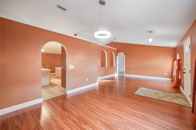 spare room featuring light wood-type flooring and vaulted ceiling