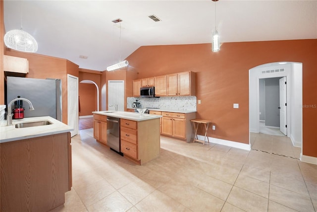 kitchen with pendant lighting, sink, vaulted ceiling, an island with sink, and stainless steel appliances