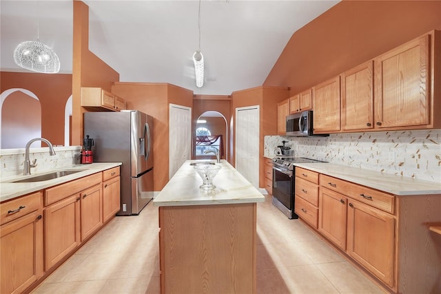 kitchen with a center island with sink, stainless steel appliances, decorative light fixtures, and sink