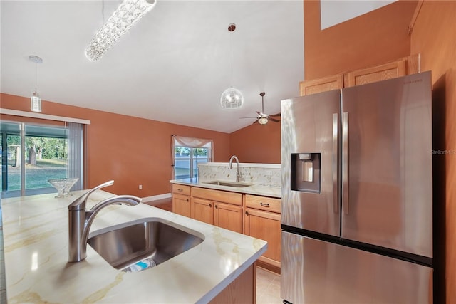 kitchen featuring stainless steel fridge, light brown cabinets, lofted ceiling, and sink