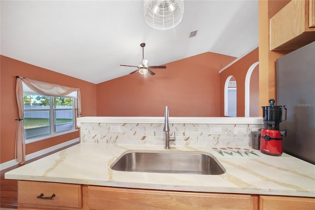 kitchen featuring light stone countertops, sink, light brown cabinets, backsplash, and vaulted ceiling