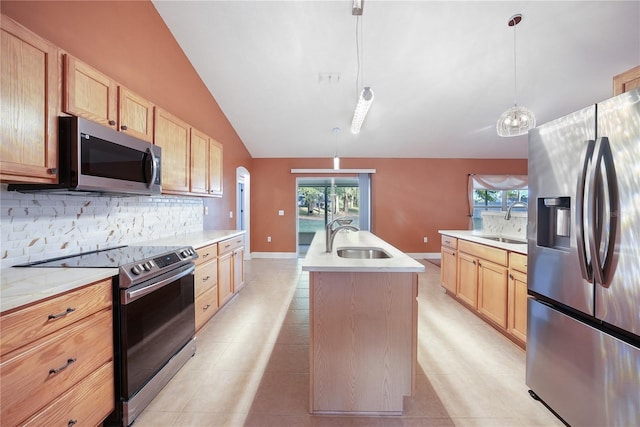 kitchen with lofted ceiling, a center island with sink, sink, appliances with stainless steel finishes, and decorative light fixtures