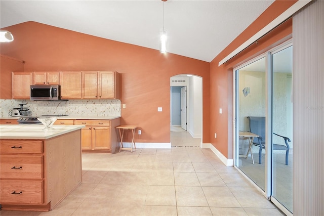 kitchen with lofted ceiling, decorative backsplash, light brown cabinetry, decorative light fixtures, and light tile patterned flooring