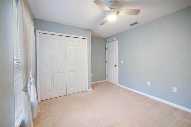 unfurnished bedroom featuring light carpet, a closet, and ceiling fan