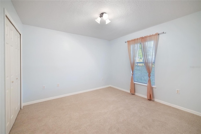 unfurnished bedroom with light colored carpet, a textured ceiling, and a closet