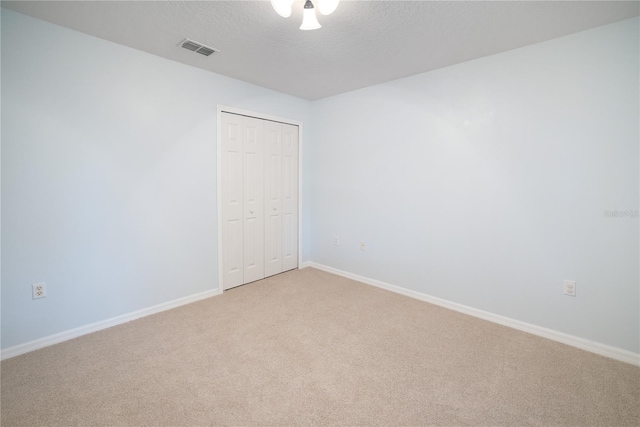 unfurnished bedroom with carpet flooring, a textured ceiling, and a closet