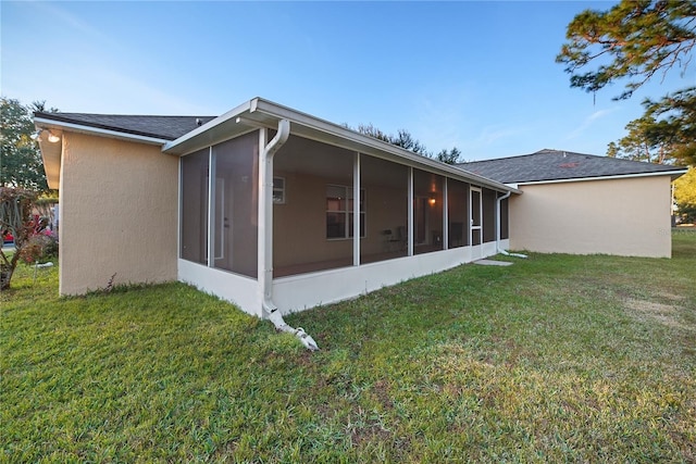 rear view of house with a sunroom and a yard