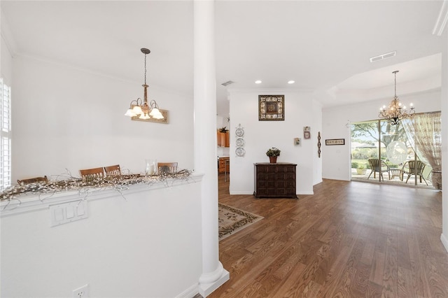 hallway with crown molding, hardwood / wood-style floors, and an inviting chandelier