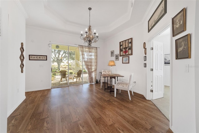 dining room with a chandelier, a raised ceiling, dark wood-type flooring, and crown molding