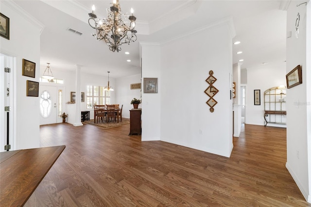 foyer entrance with an inviting chandelier, crown molding, and dark wood-type flooring