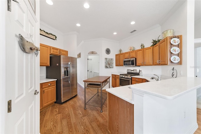 kitchen with kitchen peninsula, appliances with stainless steel finishes, light hardwood / wood-style flooring, and crown molding