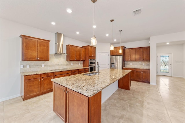 kitchen featuring backsplash, wall chimney exhaust hood, stainless steel appliances, a kitchen island with sink, and decorative light fixtures