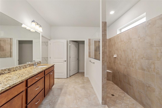 bathroom with a tile shower and vanity