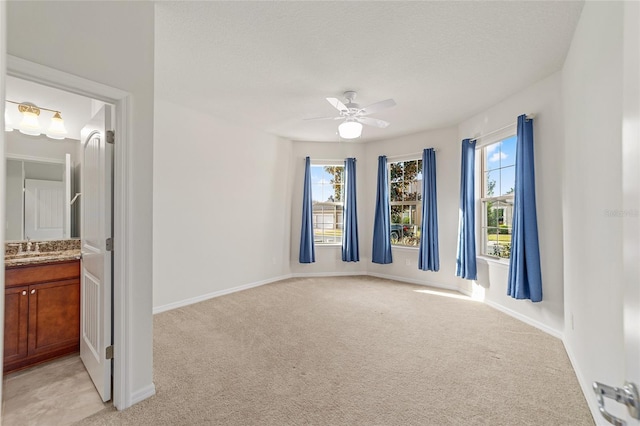 carpeted spare room with ceiling fan, plenty of natural light, and sink