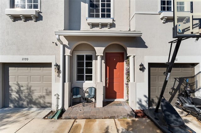 property entrance featuring an attached garage and stucco siding