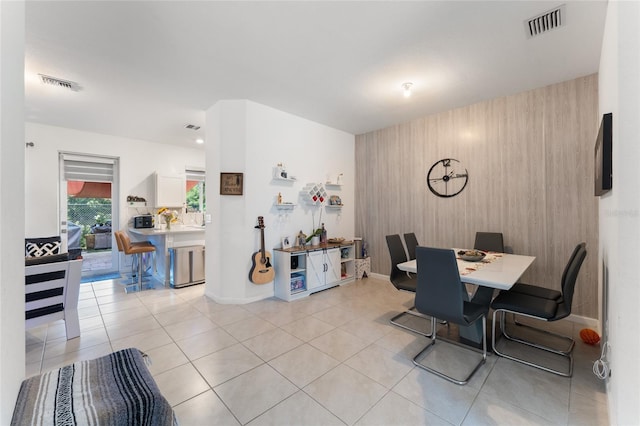 dining space featuring light tile patterned floors, an accent wall, and visible vents