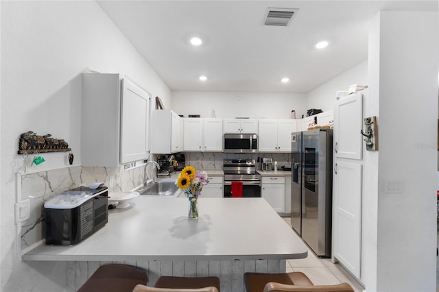 kitchen with stainless steel appliances, a breakfast bar, a peninsula, and light countertops