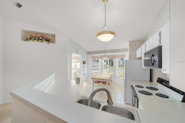 kitchen with white cabinets, decorative light fixtures, white electric stove, and vaulted ceiling