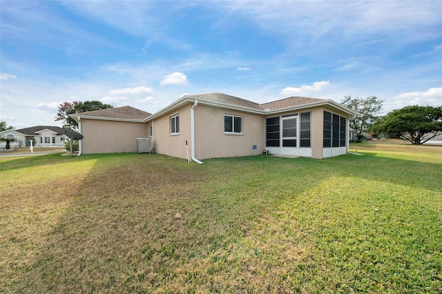 back of property featuring a lawn, central air condition unit, and a sunroom