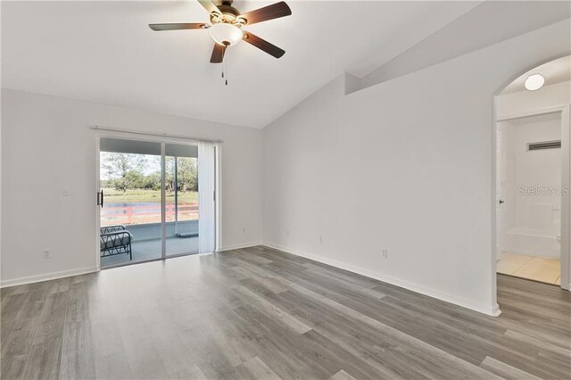 spare room with ceiling fan, wood-type flooring, and vaulted ceiling