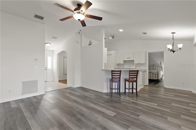 living room with ceiling fan with notable chandelier, dark wood-type flooring, and lofted ceiling