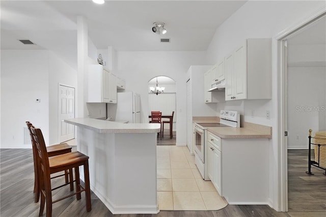 kitchen with kitchen peninsula, light wood-type flooring, a breakfast bar, white appliances, and white cabinetry