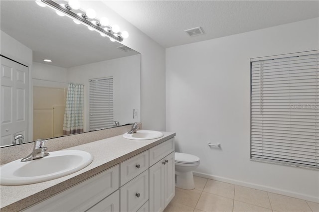 bathroom with a textured ceiling, vanity, tile patterned flooring, toilet, and curtained shower