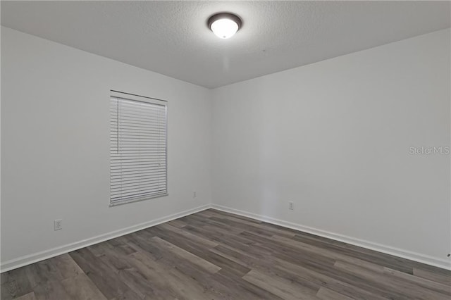 empty room featuring dark hardwood / wood-style floors and a textured ceiling