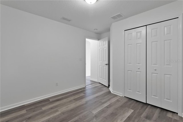 unfurnished bedroom with wood-type flooring, a textured ceiling, and a closet