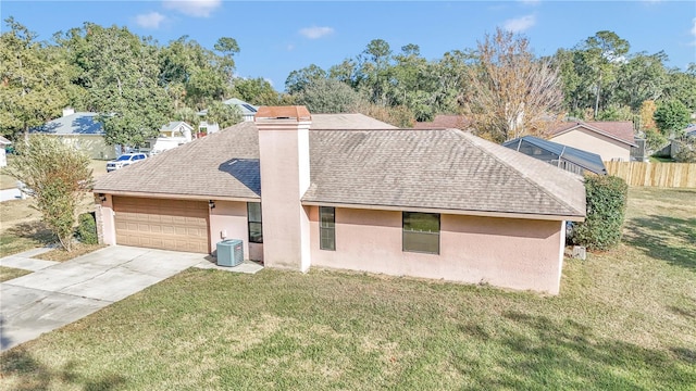 view of front of house with central AC, a front yard, and a garage