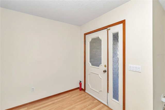 entrance foyer with light hardwood / wood-style floors and a textured ceiling