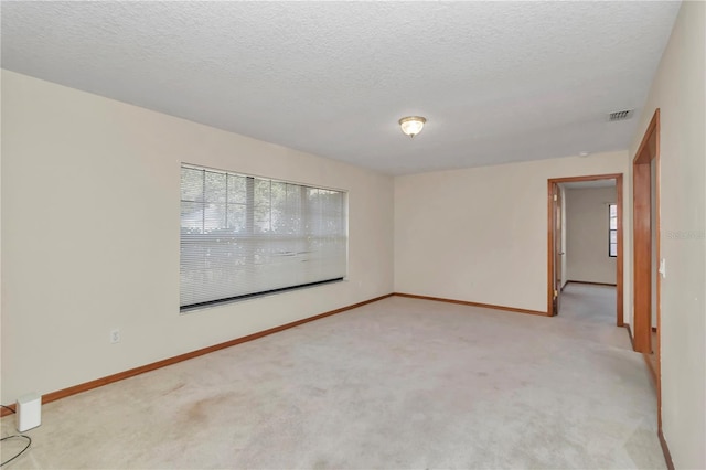 empty room with light colored carpet and a textured ceiling