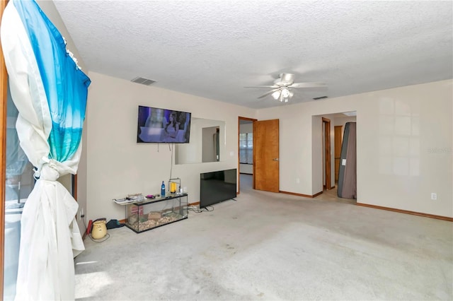 unfurnished living room featuring ceiling fan, carpet floors, and a textured ceiling