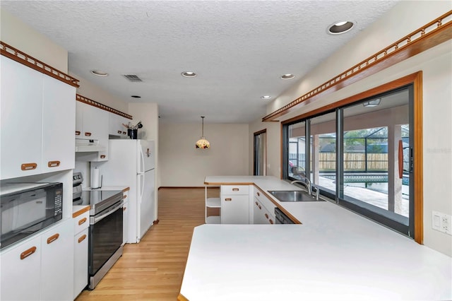 kitchen featuring electric stove, sink, decorative light fixtures, white cabinetry, and black microwave