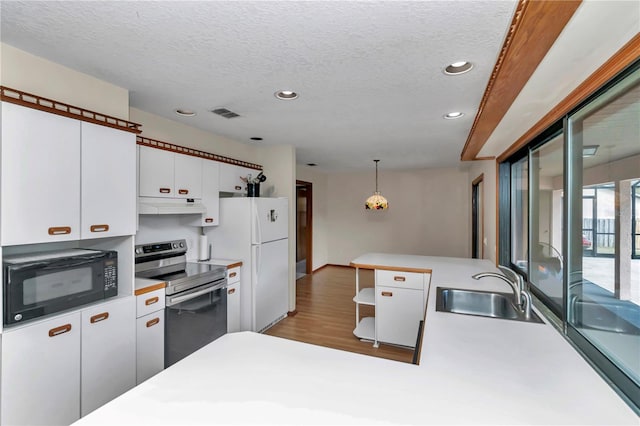 kitchen with sink, white refrigerator, white cabinetry, hanging light fixtures, and stainless steel range with electric cooktop