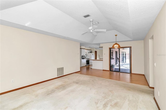 unfurnished living room featuring hardwood / wood-style floors, ceiling fan, lofted ceiling, and a textured ceiling