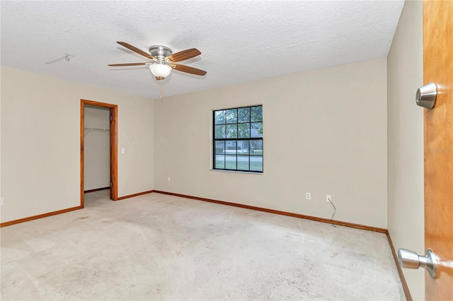 empty room featuring a textured ceiling, light colored carpet, and ceiling fan