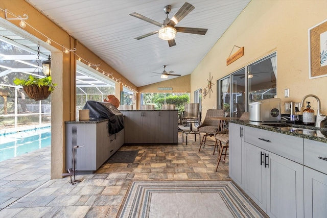 view of patio / terrace with a lanai, area for grilling, ceiling fan, and a wet bar