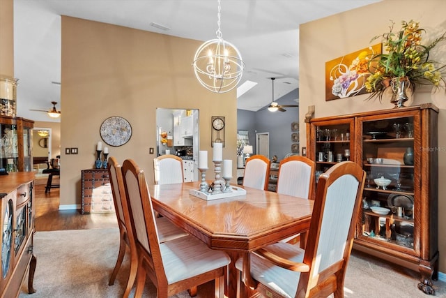 dining area featuring vaulted ceiling, ceiling fan with notable chandelier, and hardwood / wood-style flooring