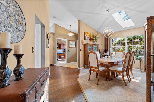 dining room featuring hardwood / wood-style flooring, a notable chandelier, and vaulted ceiling with skylight