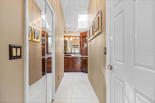 hallway featuring sink and light tile patterned flooring