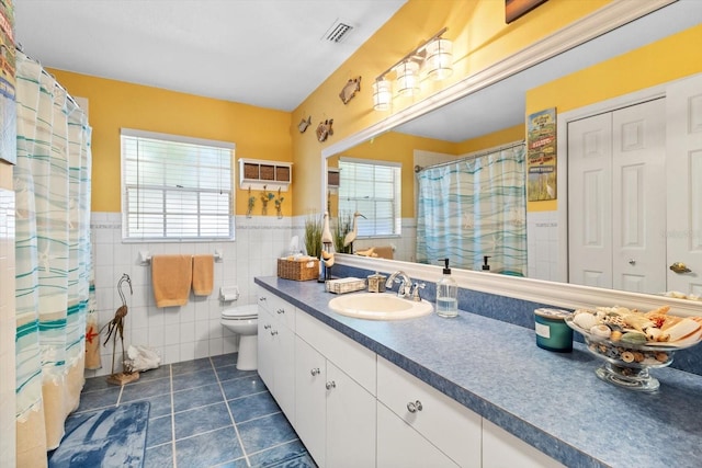 bathroom featuring tile patterned floors, vanity, a healthy amount of sunlight, and tile walls