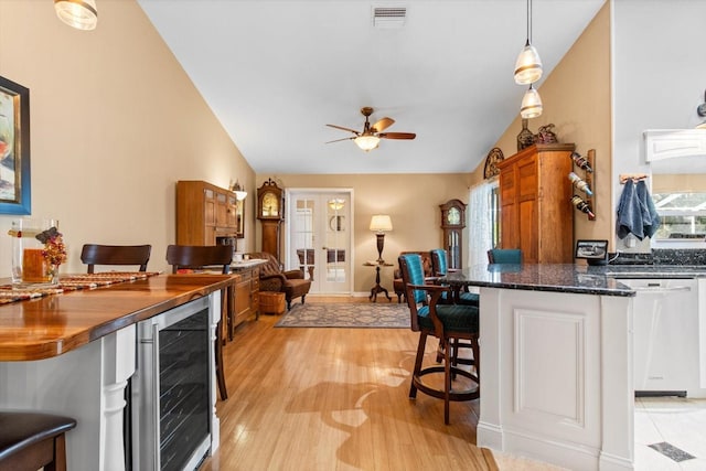 kitchen with dishwasher, beverage cooler, pendant lighting, vaulted ceiling, and a breakfast bar