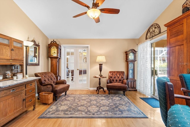 sitting room with ceiling fan, light hardwood / wood-style floors, french doors, and vaulted ceiling