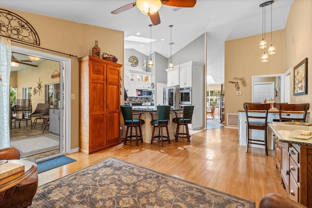 interior space featuring ceiling fan, light hardwood / wood-style flooring, high vaulted ceiling, and plenty of natural light