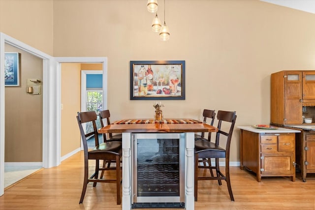 dining area featuring light hardwood / wood-style floors, lofted ceiling, and beverage cooler